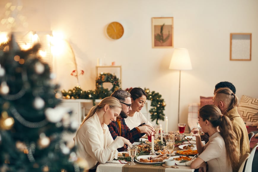 A scene of a family eating dinner around a table during the holidays.