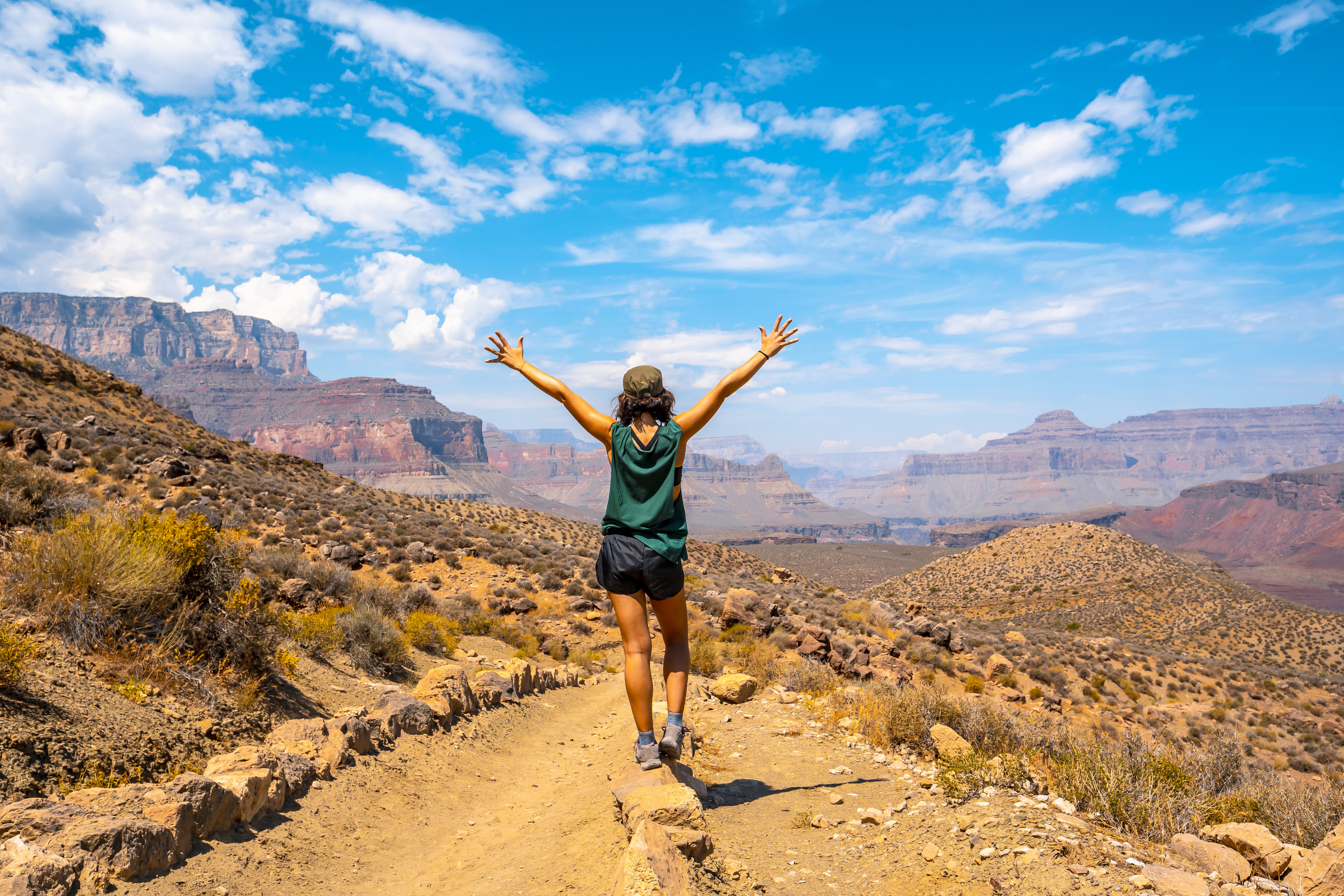 woman outside with arms raised to the sky with the grand canyon as a background