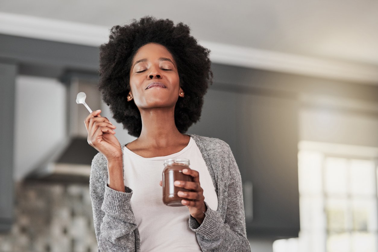 A young woman enjoying a bite of dark chocolate pudding, a food that naturally increases dopamine and serotonin.